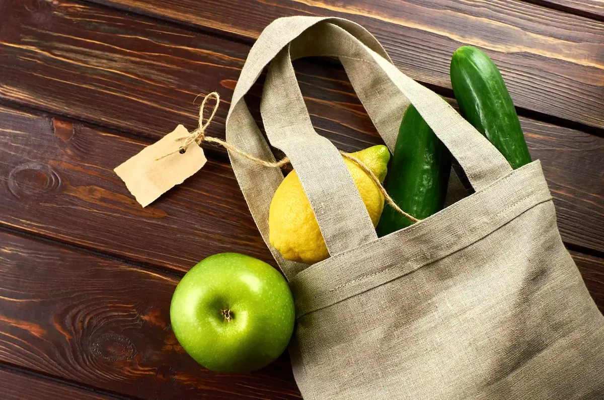 Economia green: busta ecologica con mela verde, limone e cetriolo, a rappresentare il consumo consapevole