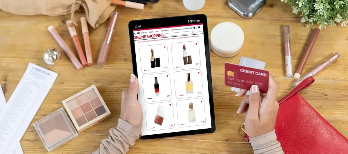 Persona che acquista prodotti cosmetici online su tablet, usando una carta di credito, rappresentando il mercato e-commerce della bellezza
