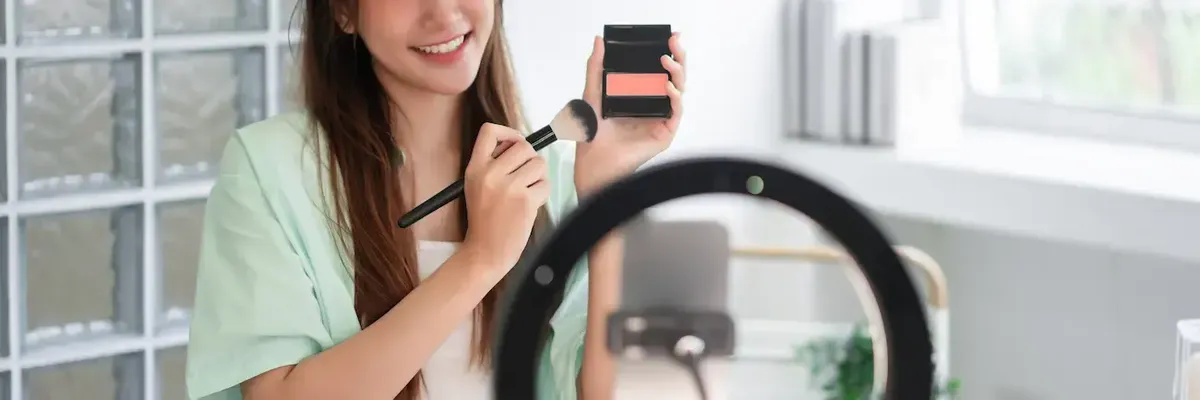 Influencer di cosmetica che crea contenuti per i social media, mostrando un prodotto di make-up, a simboleggiare il marketing digitale nel settore beauty