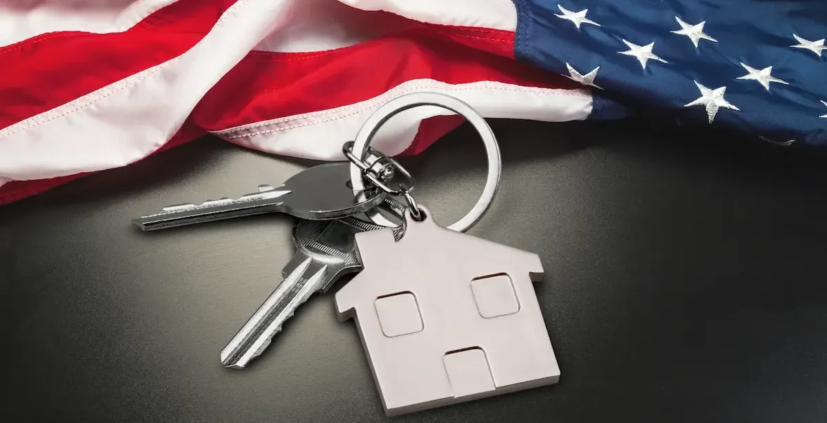 Chiavi di casa con portachiavi a forma di casa sulla bandiera americana, che simboleggiano l'investimento immobiliare negli USA
