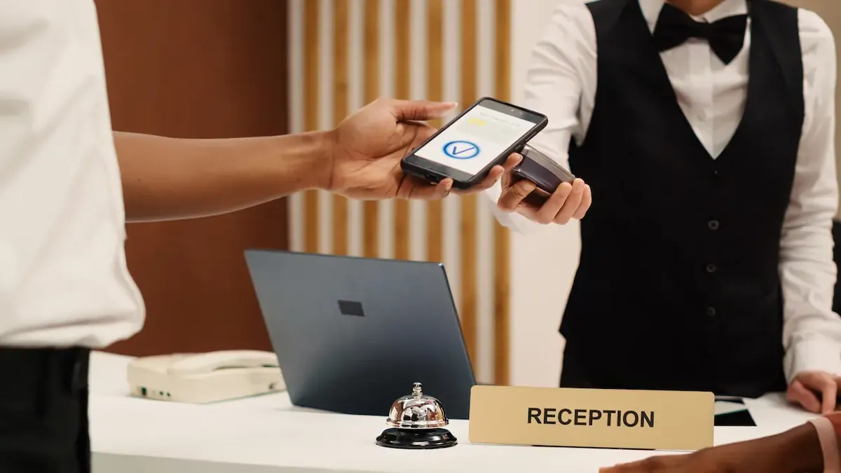 Un cliente che utilizza uno smartphone per interagire con un terminale POS alla reception di un hotel, illustrando il check-in digitale e i servizi smart