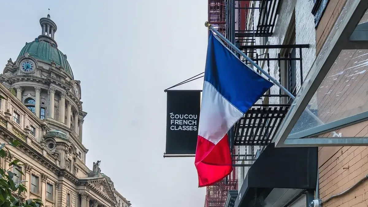 "Bandiera francese e insegna 'Coucou French Classes' in un quartiere di New York, simbolo di Little Paris