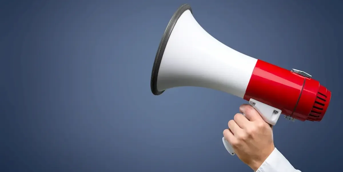 Mano che tiene un megafono rivolto in silenzio, simboleggiando lo stealth marketing e la comunicazione silenziosa.