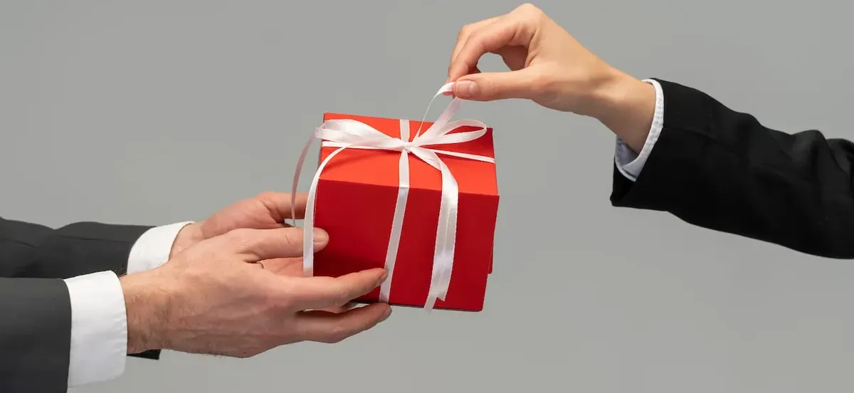 Mano che offre un pacco regalo rosso, simbolo di ricompensa e gratitudine in un programma fedeltà