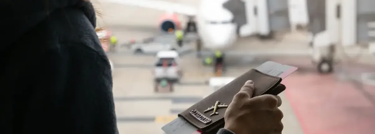 Viaggiatore in aeroporto con passaporto e carta d'imbarco, in attesa di controlli