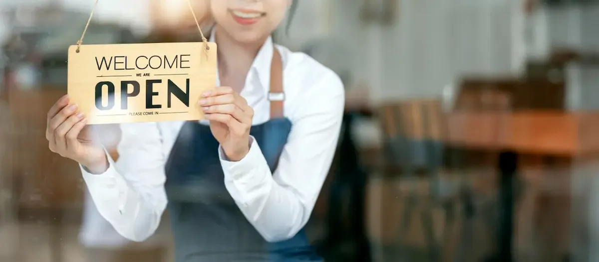 cameriera con un cartello 'open', che sta a simboleggiare l'apertura del nuovo ristorante
