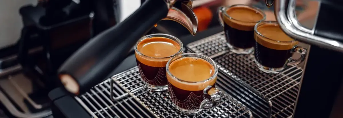 Macchina da caffè espresso professionale che eroga caffè con cremina in tazzine di vetro