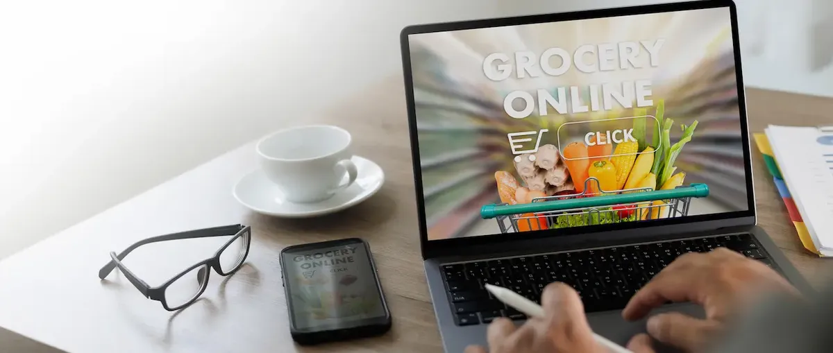 Uomo al laptop che fa la spesa online, schermo con carrello e prodotti alimentari freschi, e-commerce alimentare