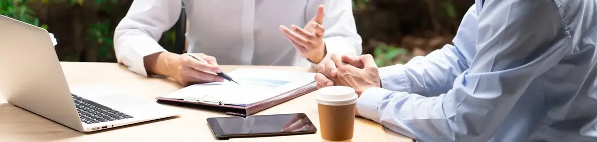 Incontro di consulenza individuale tra due professionisti su strategie di business, con l'uso di un laptop e documenti