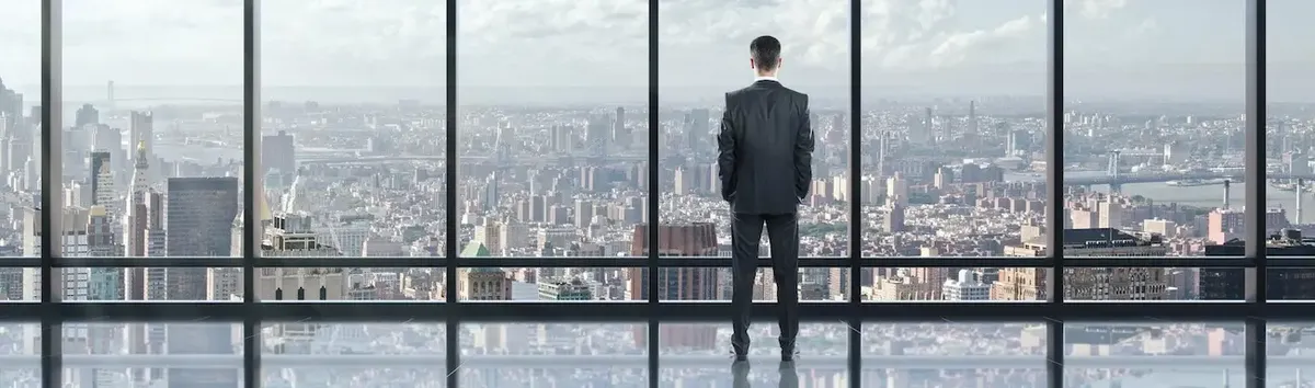 Professionista in un ufficio di New York con vista sullo skyline, a simboleggiare l'opportunità di carriera per un commercialista italiano.