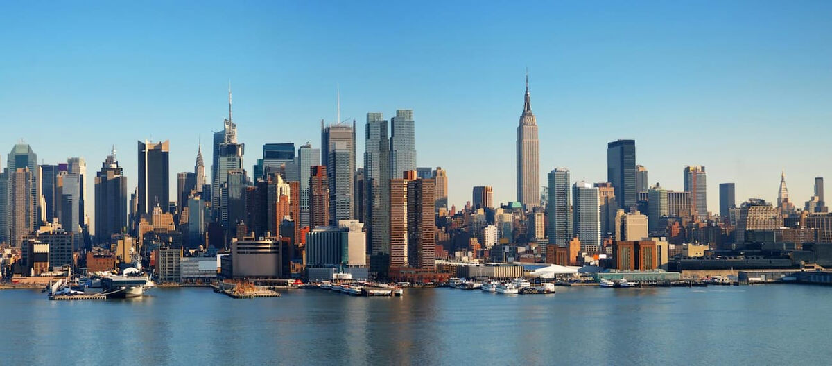  Panorama della skyline di New York City dal fiume, con grattacieli iconici e imbarcazioni, a simboleggiare la grandezza del mercato americano per il cibo italiano