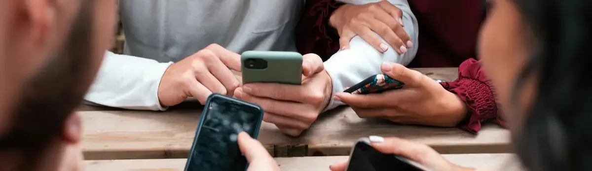 Un gruppo di giovani Millennials che interagiscono con i loro smartphone, a simboleggiare la sharing economy e la collaborazione digitale