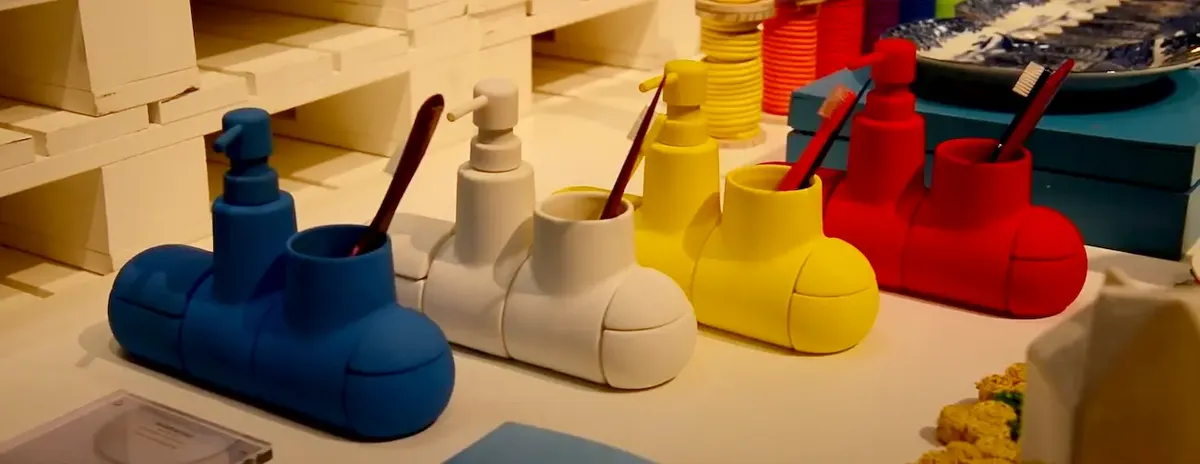 Seletti North America e' sulla copertina del catalogo di NY NOW Portaspazzolini “Submarino” colorati a forma di sottomarino, con dosatore e spazio per spazzolini, esposti su un tavolo.