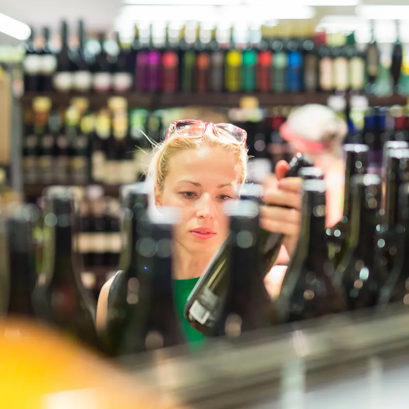 una consumatrice di vino acquista una bottiglia italiana in un negozio negli Usa